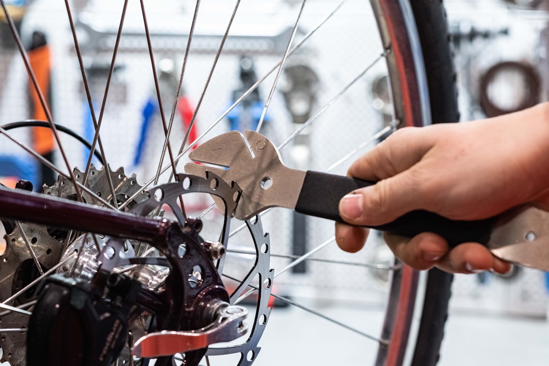 a person is holding a wrench and working on a bicycle wheel